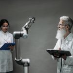 Dois cientistas trabalham com um braço robótico em um laboratório.