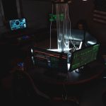 Equipe de profissionais trabalha diante de computadores em uma sala escura, em atividade relacionada à segurança cibernética