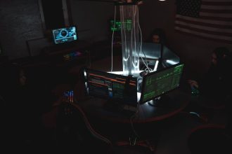 Equipe de profissionais trabalha diante de computadores em uma sala escura, em atividade relacionada à segurança cibernética