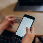 Pessoa segura um smartphone e um cartão de crédito, representando uma compra online pelo celular.