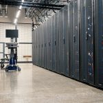 Armários metálicos com servidores, equipamentos de rede e cabos em um data center moderno.