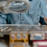 Inspeção de um circuito eletrônico com lupa e ferramentas técnicas.
