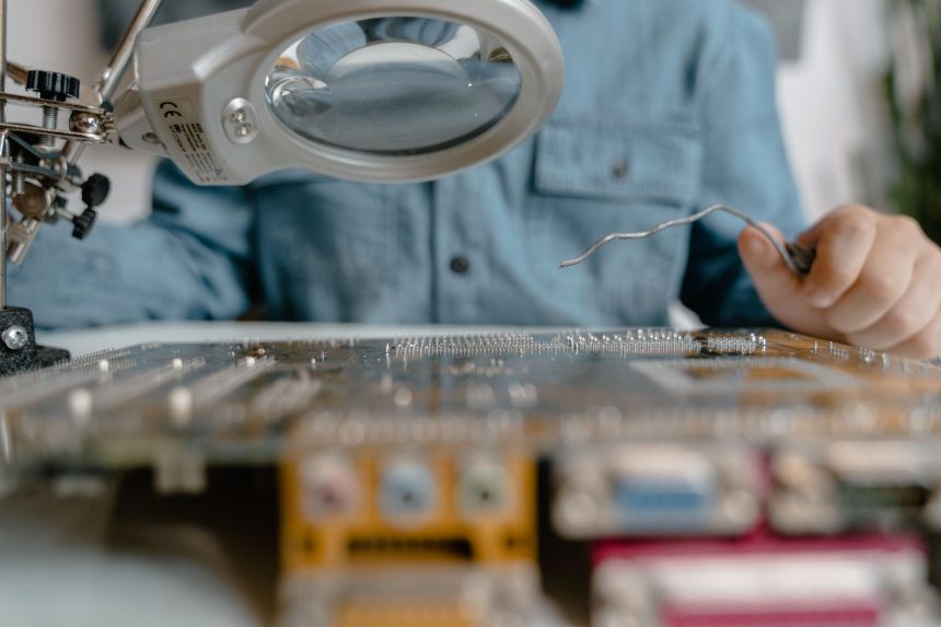Inspeção de um circuito eletrônico com lupa e ferramentas técnicas.